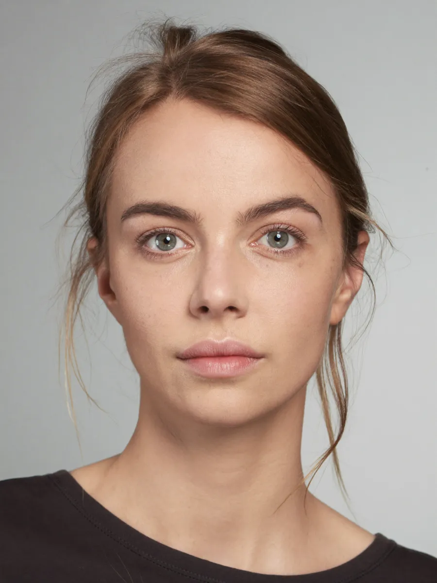 A face photographed square to the camera with the measurement grid drawn over it: a vertical midline, the three horizontal lines that divide the face into thirds, and dots on the brows, eyes, cheeks, nose base, mouth and chin.